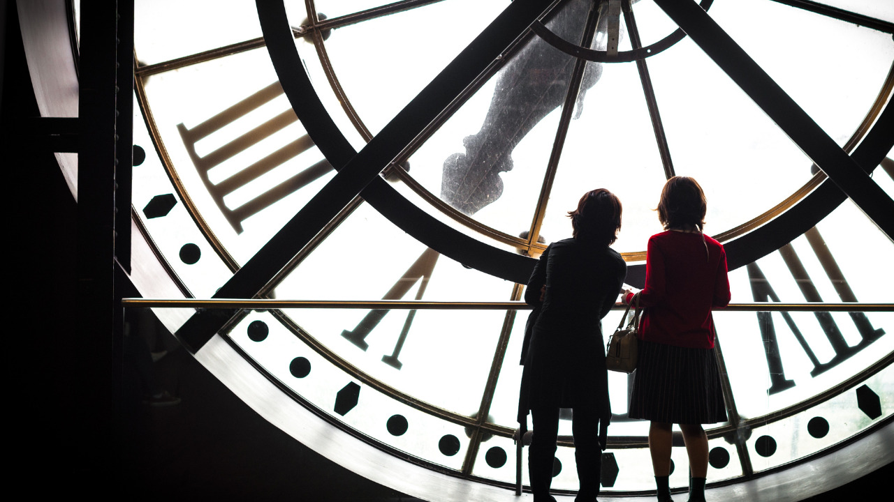 女の子と男の子が時計塔の中から文字盤を見ている